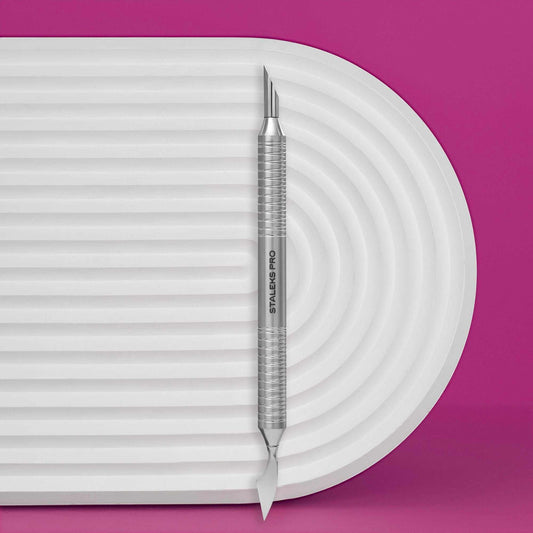 Staleks Pro Expert cuticle pusher with ergonomic handle on textured surface.